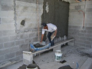 Marcelino plastering the walls of the new house